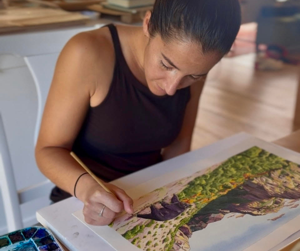 Woman painting a landscape on an easel in a home setting